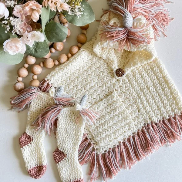 A childrens crochet unicorn poncho with matching unicorn socks.
