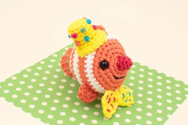 A crochet  clownfish wearing a party hat.