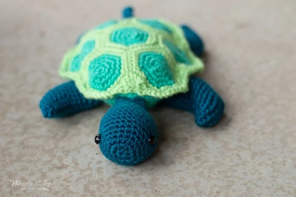A baby sea turtle amigurumi with a multicloured shell.