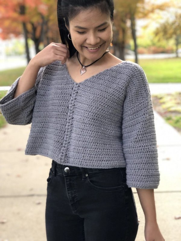 Grey crochet cropped sweater with a v-neck.