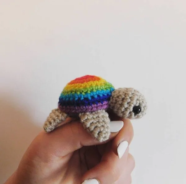 A crochet turtle made in the Pride rainbow colours.