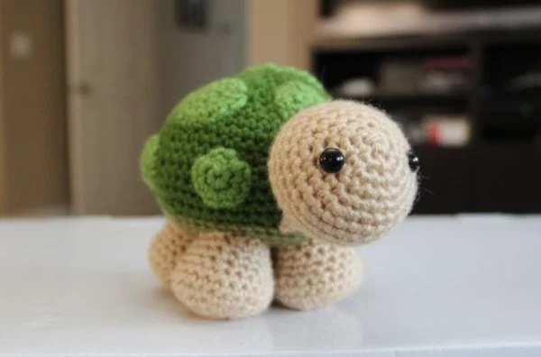 A close-up of a standing crochet turtle toy.