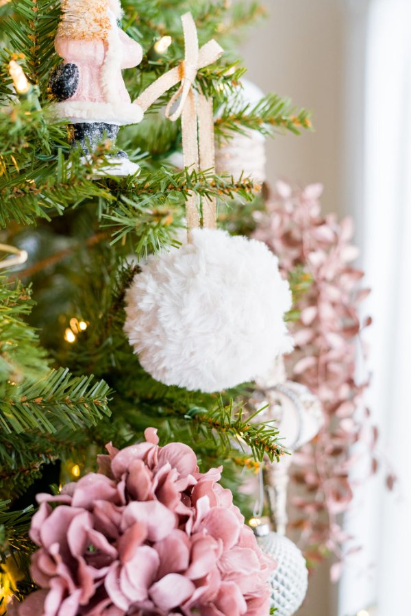 A fuzzy faux fur crochet Christmas ball handing on a tree.