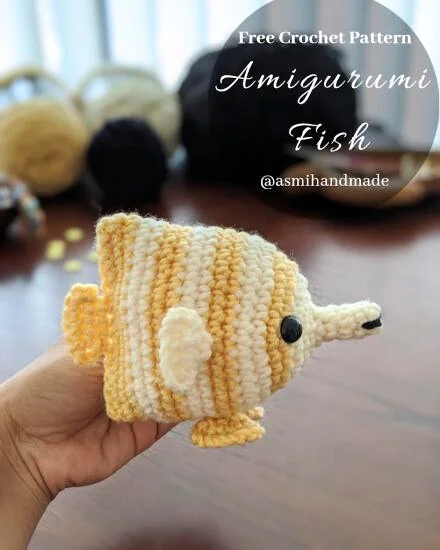 Yellow-striped crochet fish held in a hand.