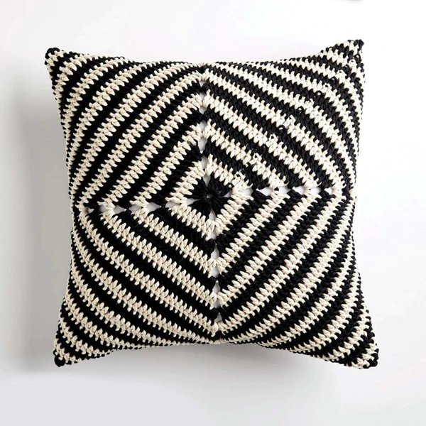A graphic black and white crochet granny square pillow.