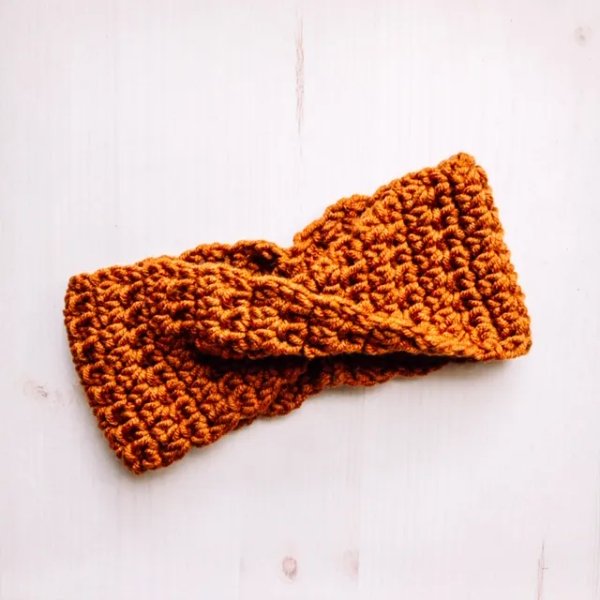 A burnt orange twisted crochet headband.