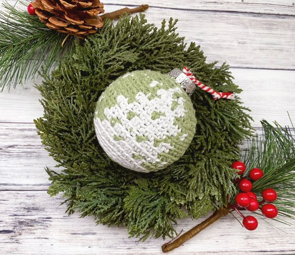 A green and white colourwork crochet Chritmas bauble.