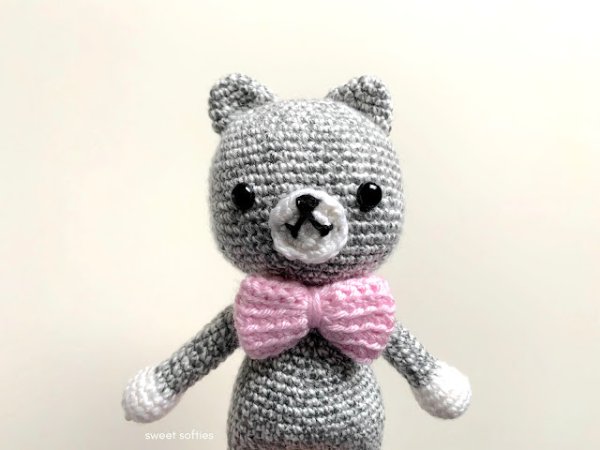A grey amigurumi cat with a pink bow tie.