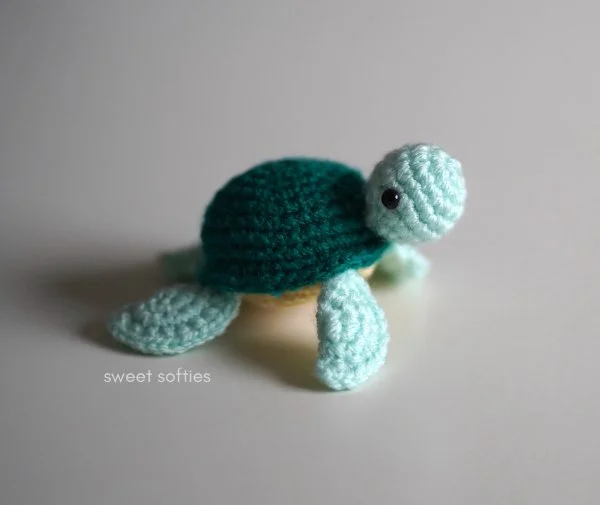 A crochet turtle in different shades of green.