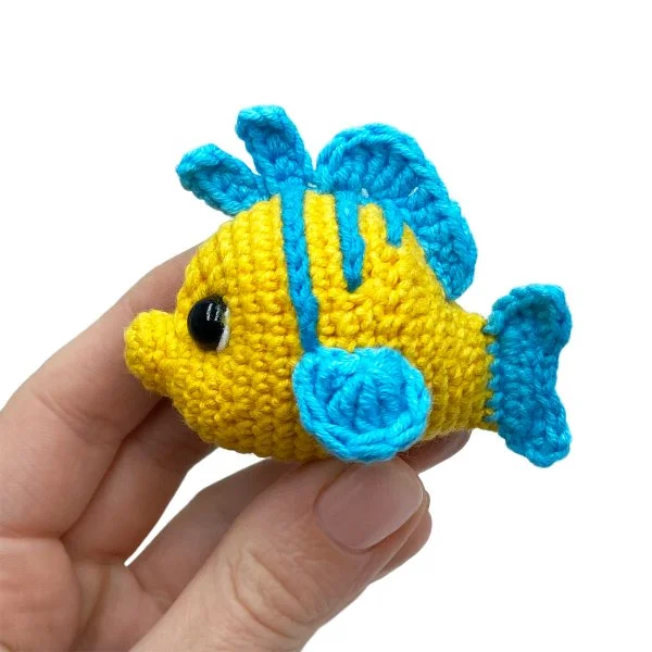 A blue and yellow crochet flounder fish toy.