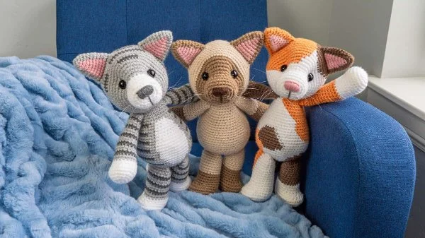 Three crochet cat toys, a calico cat, a tabby cat, and a Siamese cat.
