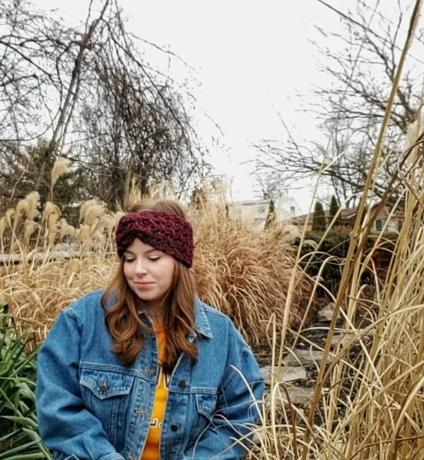 A woman outdoors wearing a warm crochet earwarmer.