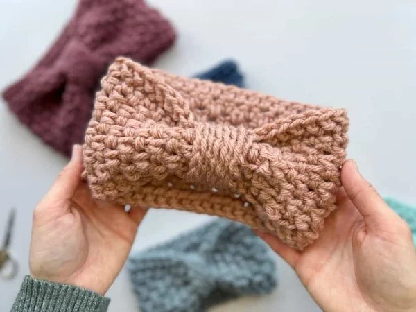 A woman holding a textured crochet headband.