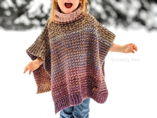 A child wearing a crochet poncho in the snow.
