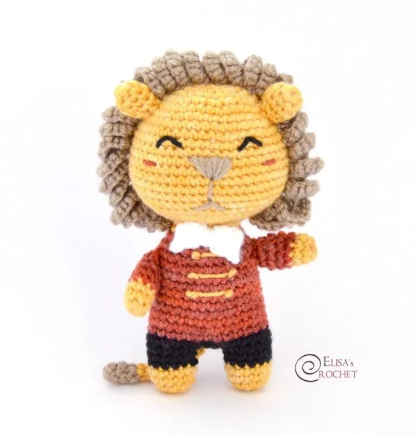 A crochet lio toy in a circus ring masters outfit.