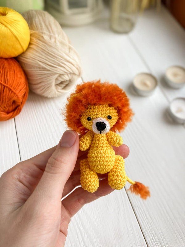 A tiny crochet lion toy held in a hand.