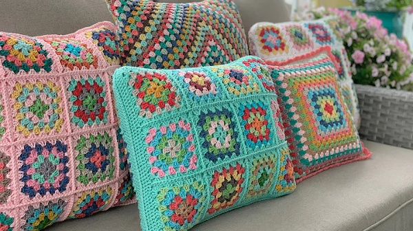 A pile of crochet granny square pillows.
