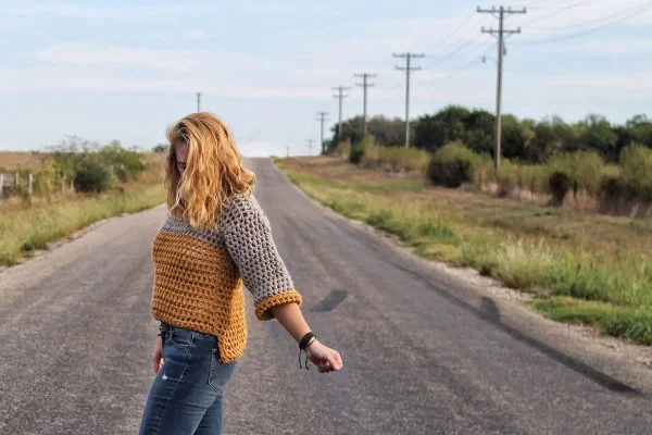 A woman wearing a colour-blocked crochet cropped sweater.