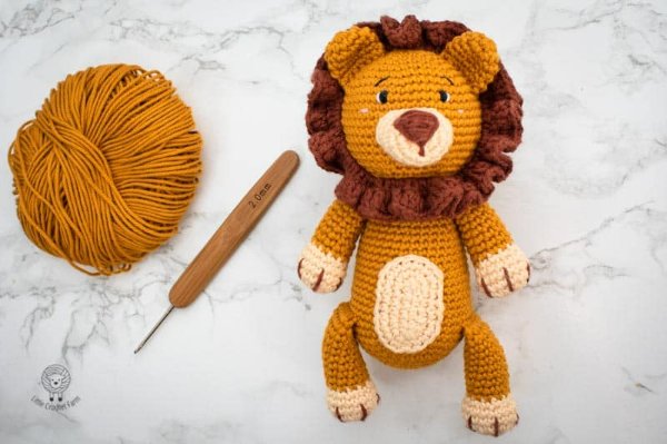 A crochet lion with a ball of yarn and a crochet hook.