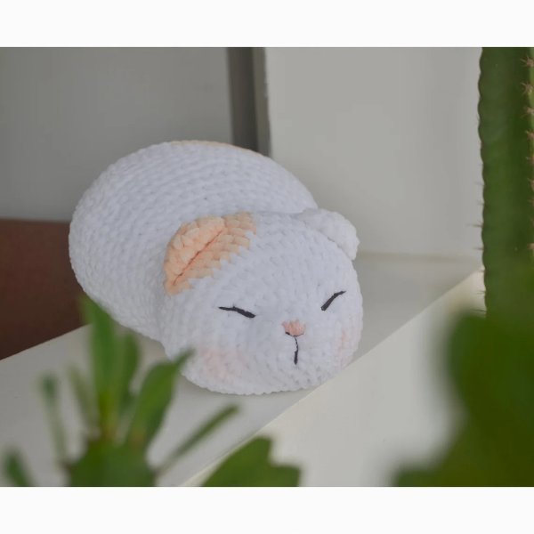 A fat crochet cat with a sweet facial expression.