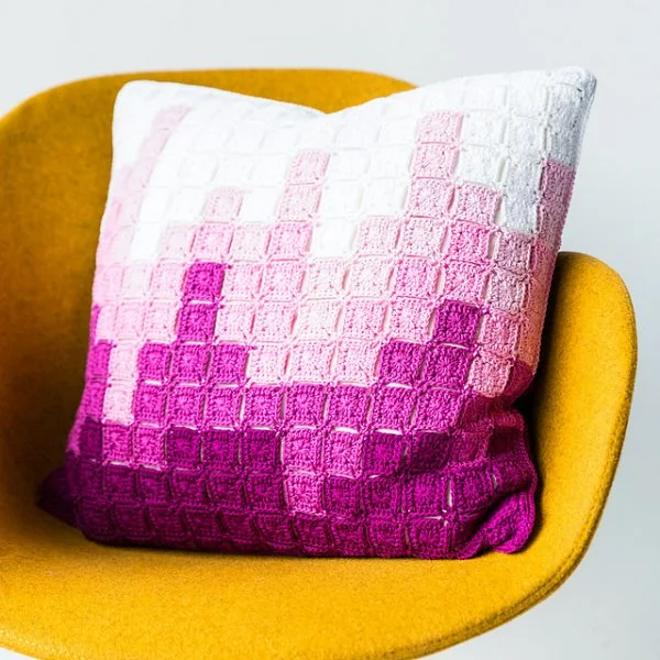 Crochet pillow with graphic skyline design made with granny squares.