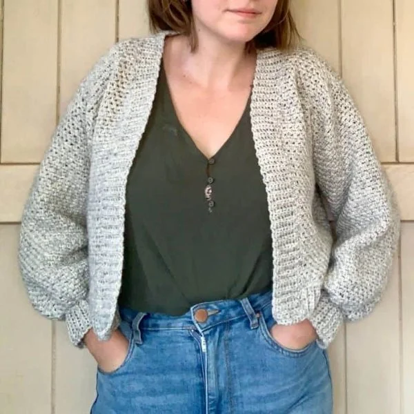 A woman wearing a cropped crochet cardgigan with jeans and a dark coloured tee.
