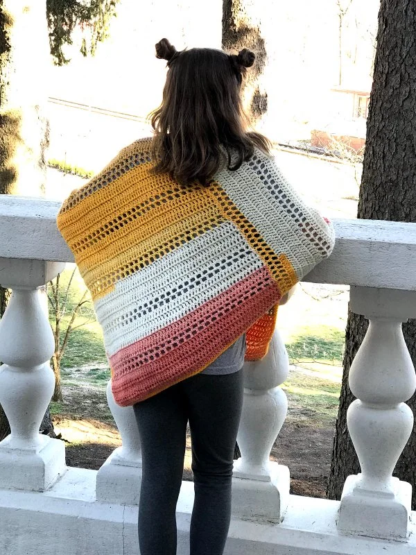 Back view of a young child wearing a crochet poncho.
