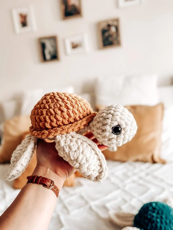 A neutral coloured, modern crochet turtle toy.