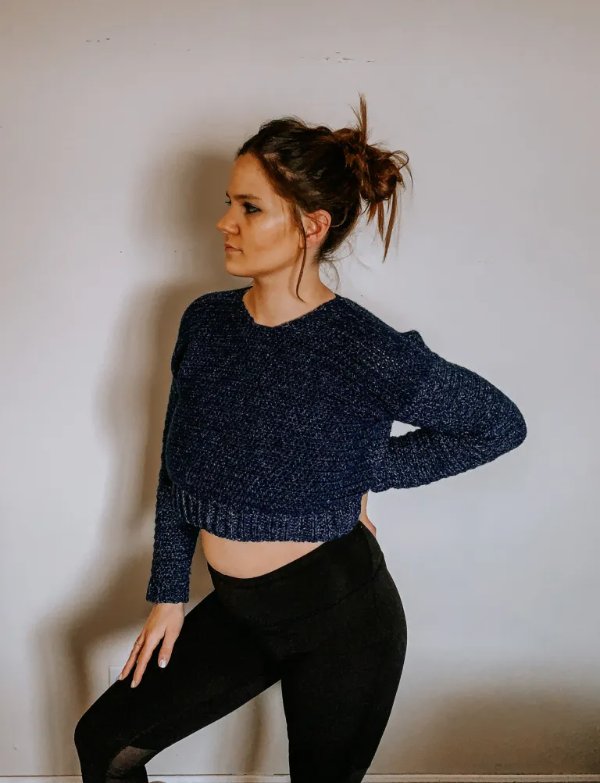 Side view of a woman wearing a cropped crochet sweater with black jeans.