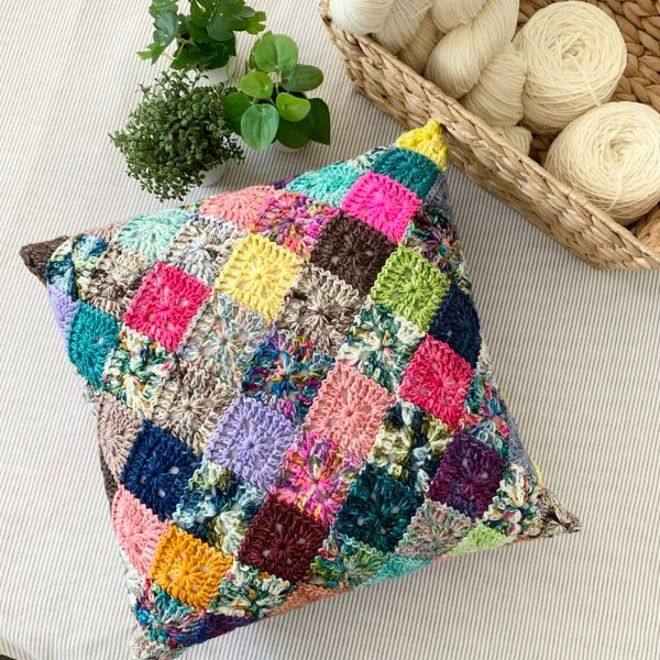 A brightly coloured scrap yarn granny square pillow.