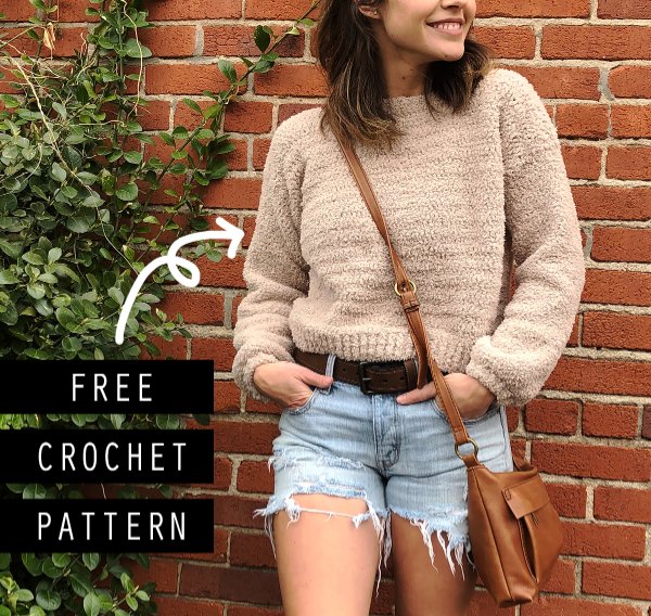 A woman wearing a crochet cropped sweater with cut off jean shorts.
