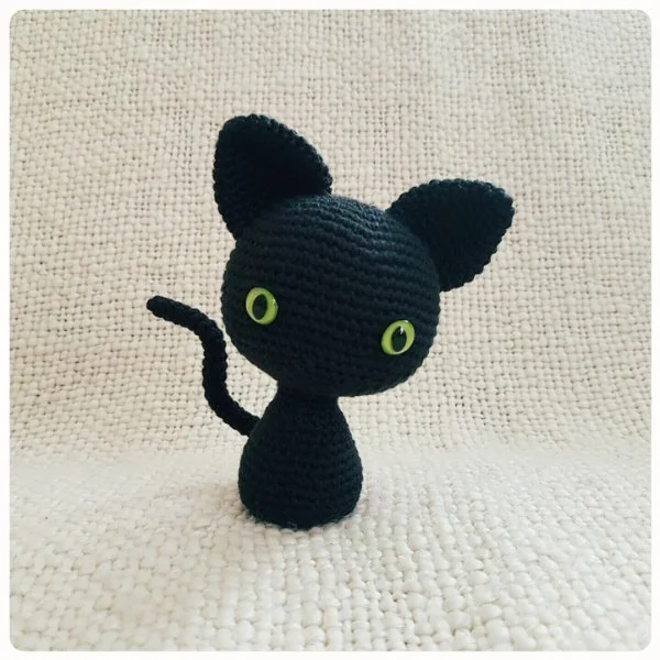 A black crochet cat with a large head.