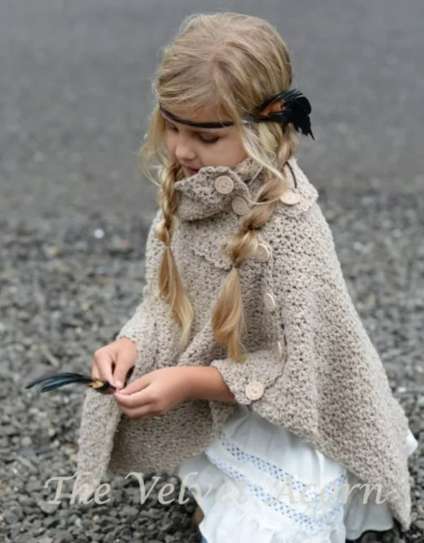 A young girl wearing a crochet poncho with a detachable cowl.