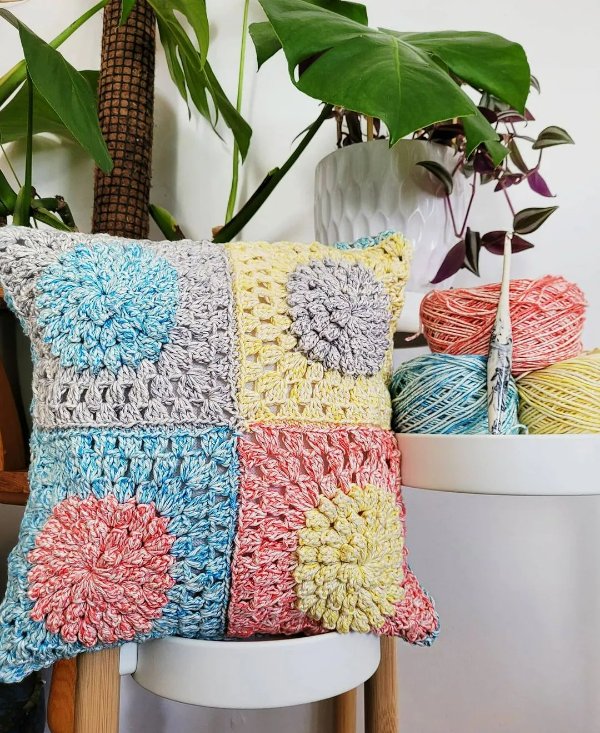 A crochet pillow made with four large granny squares.