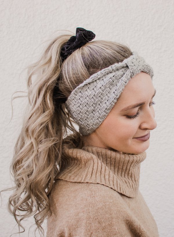 A woman wioth a long ponytail wearing a grey crochet headband.