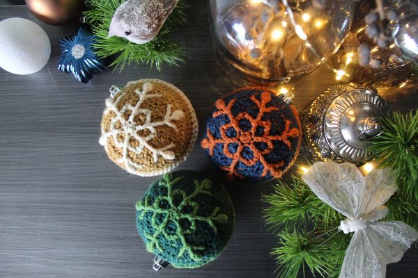 Crochet Christmas baubles with an intricate snowflake design.