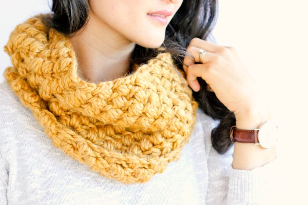 A closeup image of a yellow crochet cowl worked in the bean stitch,