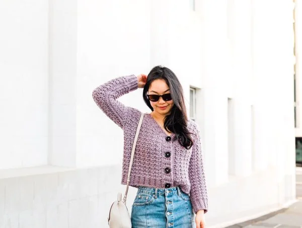 A woman wearing a chunky crochet button-up cardigan.