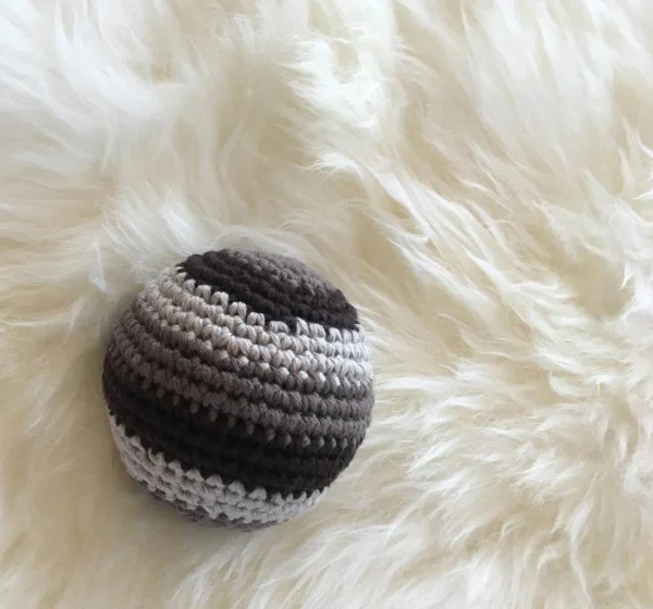 A grey striped crochet ball toy.