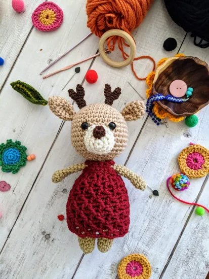 A crochet deer in a red dress.