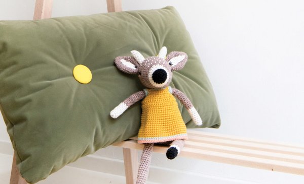 A crochet deer wearing a yellow dress.