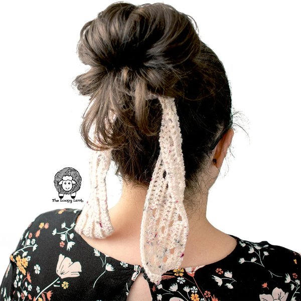 A woman wearing a cream coloured crochet hair scarf round a bun.