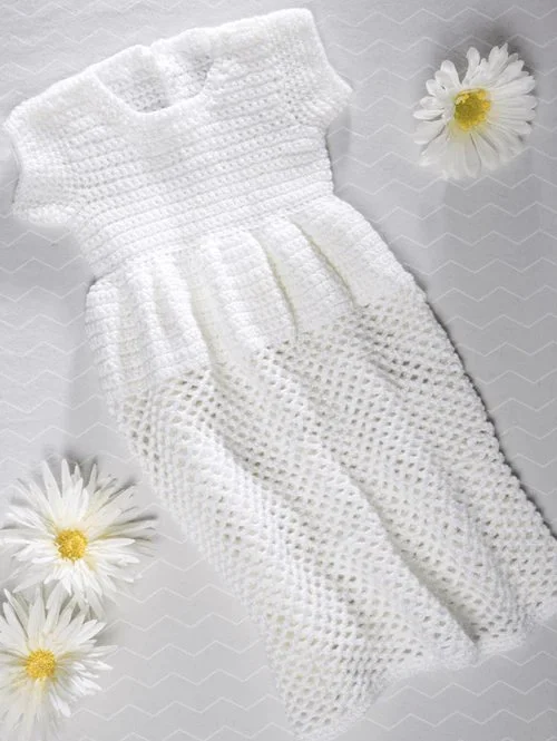 Long white crochet christening gown flatlay with daisies.