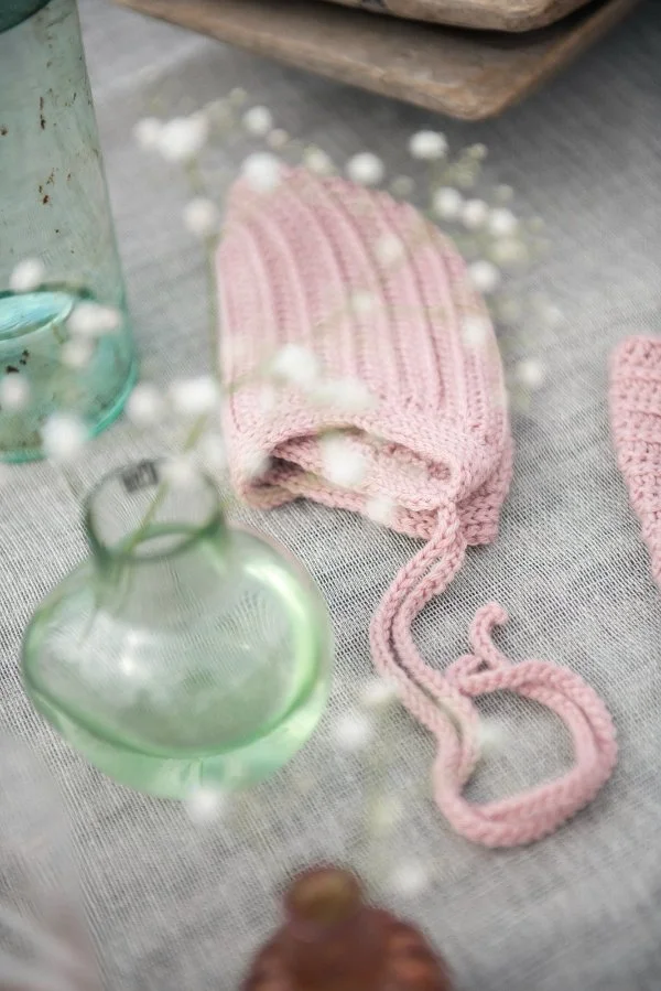 A pale pink ribbed crochet bonnet.