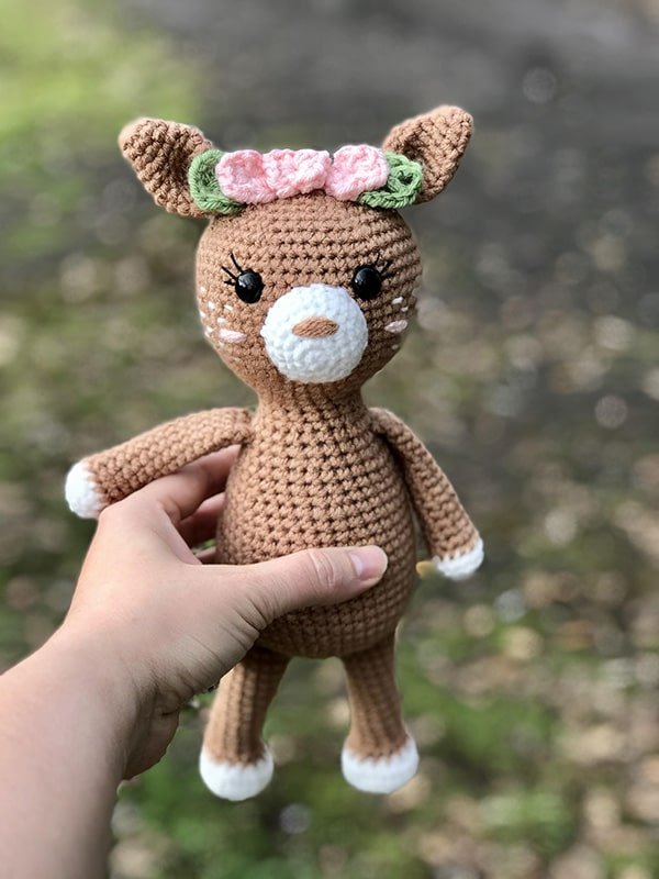A crochet deer toy with a flower garland.