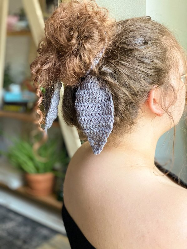 Side view of a woman wearing a crochet hair scraf round a mesy bun.