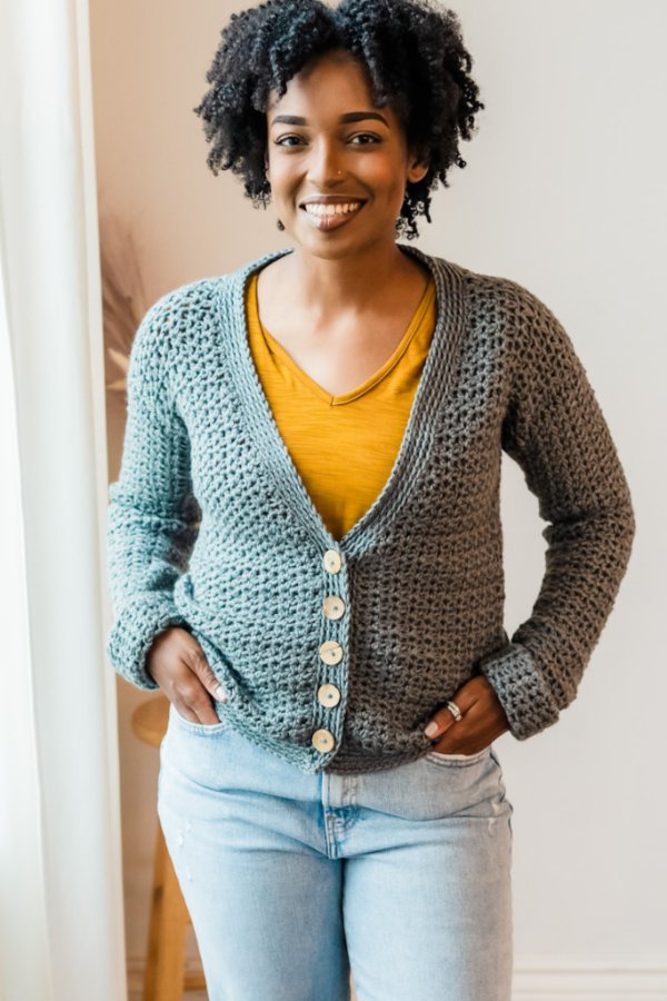 A woman wearing a crochet Grandpa button-up sweater with jeans.
