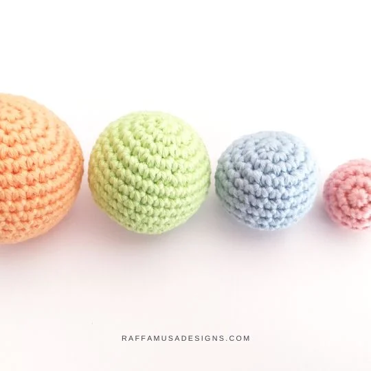 Four pastel coloured crochet balls in different sizes.