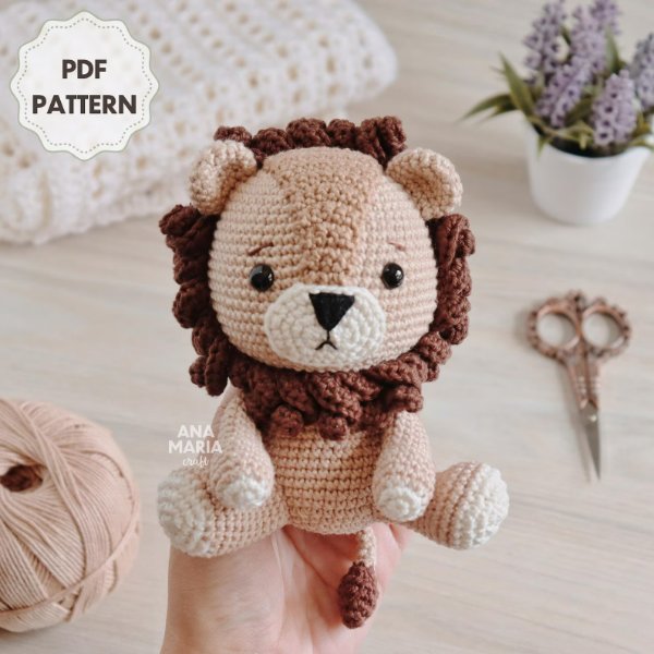 A cute crochet lion amigurumi held on someones hand.
