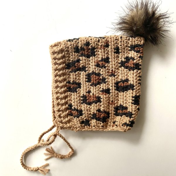 A leopard-print crochet baby bonnet.